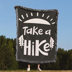 a person standing in front of a black and white sign that says take a hike