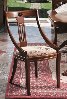 a wooden chair sitting on top of a red rug next to a table and chairs