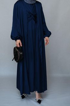 Introducing the Vidonia 2 Piece Luxury Abaya from Annah Hariri, the epitome of sophistication and style. This stunning abaya set is crafted from high-quality satin fabric, ensuring both comfort and durability. The Navy color exudes luxury and will leave a lasting impression wherever you go.The abaya features a maxi slip dress with maxi sleeves that provide full coverage and comfort. The wrap bodice adds a touch of elegance and femininity, while the elasticated cuffs offer a secure and snug fit. Elegant Solid Color Abaya For Eid, Elegant Floor-length Solid Abaya, Formal Long Sleeve Silk Abaya, Eid Evening Solid Color Abaya, Elegant Satin Maxi Abaya, Satin Floor-length Abaya For Eid, Elegant Silk Floor-length Abaya, Formal Blue Floor-length Abaya, Eid Satin Maxi Dress