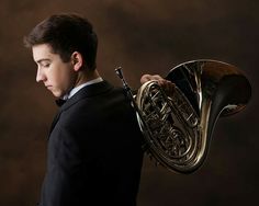 a young man in a tuxedo holding a french horn