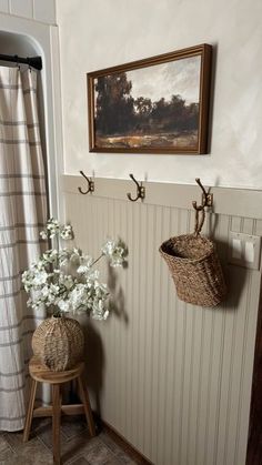 two baskets are hanging on the wall next to a stool with flowers in front of it