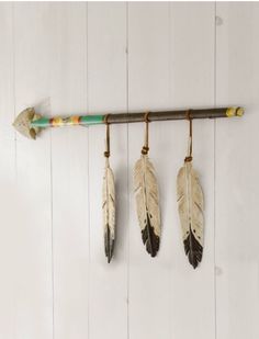 three feathers hanging on a wall with an arrow