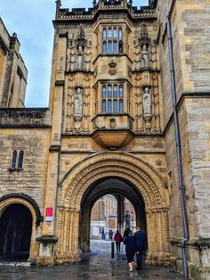 two people are walking into an old castle like building with stone arches and arched doorways