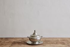 a silver pot sitting on top of a wooden table