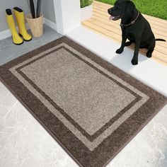 a black dog sitting on the floor next to a brown and beige rug with an area rug