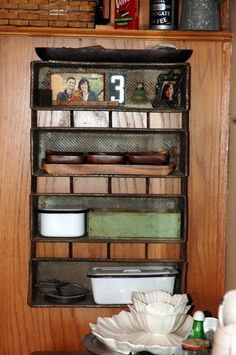 a wooden shelf filled with plates and bowls on top of a table next to a wall