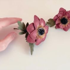 two pink flowers are being held by someone's hand