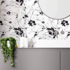 a white and black floral wallpaper with circular mirror on the sideboard next to it