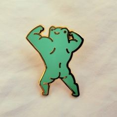 a green brooch with a bear on it's back and arms in the air