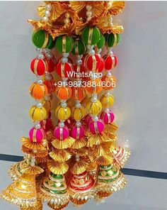 a bunch of colorful bells hanging from the side of a wall in front of a window