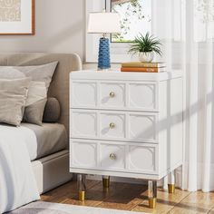 a white dresser with gold legs and a blue potted plant sitting on top of it