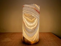 a marbled vase sitting on top of a wooden table next to a light bulb