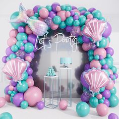 a birthday party with balloons and confetti in the shape of mermaids, under an arch that says let's party