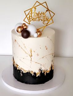 a white and black birthday cake with gold decorations