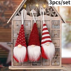 three red and white christmas gnomes hanging from a wooden house with snowflakes on the roof