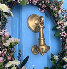 a blue door with a wreath on it and a brass knocker in the middle