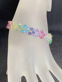 a white mannequin holding a bracelet with multicolored beads on it's wrist