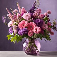 a purple vase filled with lots of different colored flowers