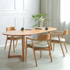 a wooden table with four chairs and a potted plant in the corner on top