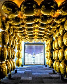 a room filled with lots of shiny gold balloons hanging from the ceiling above it's doorway