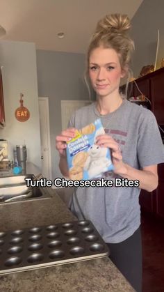 a woman standing in front of an oven holding a bag of cheesecake bites with the words turtle cheesecake bites on it