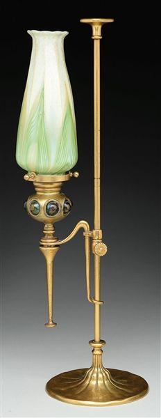 an old fashioned lamp with a green glass shade on it's side and a gold stand