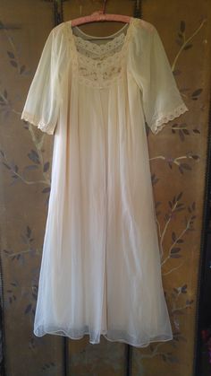 "60's lovely light beige nylon peignoir maxi nightie and sheer matching gown set. The nightie has beige lace shoulders and around front of the neck with brown eyelet embroidery across neck. The hem is lace also. The Gown is sheer double fabric. Same detail as nightie at front of the neck, it does up with two small buttons at the front of neck. mid length wide sleeves with lace at ends. Nightie : arm to arm across 18\" (36 bust) length 52\" **A few teeny tags in outer gown**" 1960s Lingerie, Hard Fits, Night Gowns, Peignoir Sets, Eyelet Embroidery, 60s Mod, Women's Nightgowns, Nightgowns, Wide Sleeves