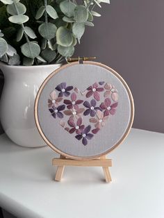 a heart made out of seashells sitting on a table next to a potted plant