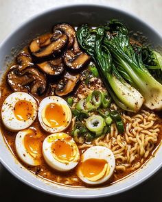 a bowl filled with noodles, eggs and broccoli on top of a table