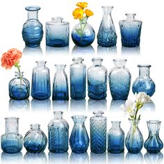 many blue vases with flowers in them on a white surface and one is empty