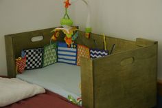 a crib made out of wood with toys in the bottom half and on top