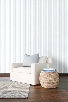 a white chair sitting on top of a wooden floor next to a rug and lamp