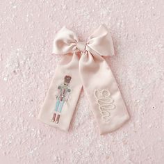 two pink bow ties with the word love on them and a small embroidered doll in the middle