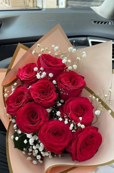 a bouquet of red roses sitting on top of a car seat in front of a window