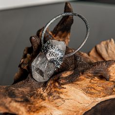 a diamond ring sitting on top of a piece of wood with a tree branch in the background