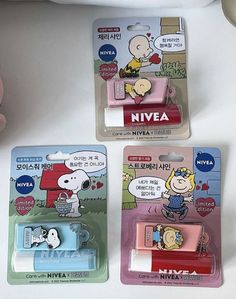 three cartoon characters are in plastic packaging on a white surface, one is holding a cell phone and the other has a clip attached to it