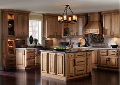 a kitchen with wooden cabinets and an island in the middle, surrounded by wood flooring