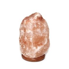 a large pink rock sitting on top of a wooden stand next to a white wall