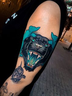 a man with a tattoo on his arm has a black bear and blue flowers around it