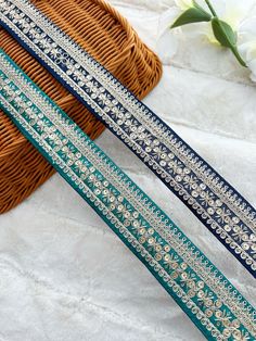 two blue and white ribbons on a table next to a wicker basket with flowers