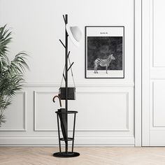 an empty room with a lamp, plant and pictures on the wall in it's corner