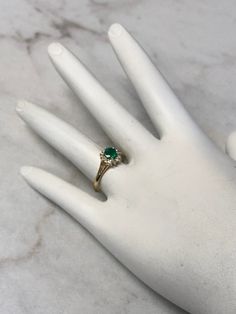 A Classic and Beautiful 14kt Yellow Gold Lady's Diamond and Emerald Ring consisting of a 5mm round genuine Emerald gemstone 3/4ct approx total weight set wtih 4 prongs in center surrounded by a halo of full cut round faceted diamonds .15ct approx total weight all prong set in finger size 6 3/4. May is the Birthstone for Emerald. This item would Retail for $2,550.00 Diamond White Emerald Ring With Round Cut, Round Emerald Ring With Diamond Accents, Diamond Ring With Prong Setting For May Birthstone, Emerald Diamond Ring With Diamond Accents, Emerald Rings With Diamond Accents Round Cut, Heirloom Solitaire Emerald Diamond Ring, 14k Gold Brilliant Cut Ring For May Birthstone, 14k Gold Rings With Brilliant Cut May Birthstone, Round Cluster Ring With Emerald And Diamond Accents