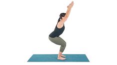 a woman is doing yoga on a blue mat with her arms up in the air