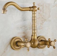 an antique brass faucet on a marble wall