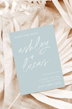 the save the date card is laying on top of some white flowers and palm leaves