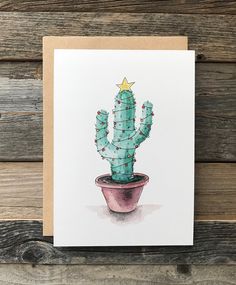 a card with a watercolor painting of a cactus in a pot on a wooden background