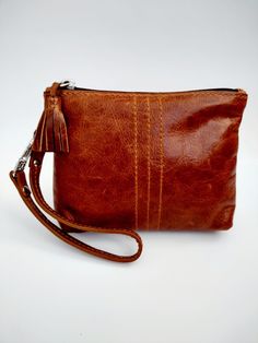 "Perfect for on-the-go essentials. Made of genuine leather, brown nylon zipper, one interior pocket, one back slide pocket and wristlet strap. Size: 5\" H x 6\" W x 1.5\" D" Everyday Brown Pouch With Zipper Pocket, Brown Rectangular On-the-go Pouch, Brown Pouch With Zipper Closure For Travel, Brown Travel Clutch With Zipper Pocket, Brown Pouch With Zipper For Daily Use, Brown Travel Clutch With Zipper Closure, Brown Clutch With Zipper Pocket For Travel, Brown Clutch With Zipper Closure For Travel, Brown Clutch With Zipper Pocket