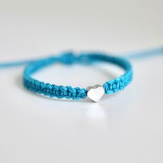 This bracelet is made of turquoise waterproof rope and a silver plated heart charm. Blue Heart Charm Jewelry For Friendship, Silver Heart Friendship Bracelets, Silver Heart-shaped Friendship Bracelets, Turquoise Bracelet With Heart Charm For Gifts, Turquoise Bracelet With Heart Charm As Gift, Turquoise Bracelets With Heart Charm As Gift, Adjustable Blue Bracelet With Heart Charm, Handmade Turquoise Heart Bracelet, Handmade Silver Heart-shaped Friendship Bracelets