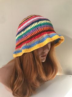 a woman wearing a multicolored crochet hat on top of a mannequin head