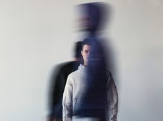 a blurry image of two people standing next to each other in front of a white wall